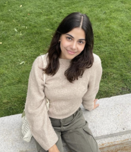 A woman smiles while sitting on a stone bench. 
